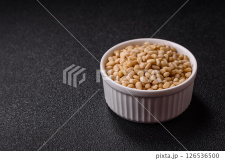 Peeled pine nuts in a bowl on a dark concrete background Peeled pine nuts in a bowl on a dark concrete background 126536500