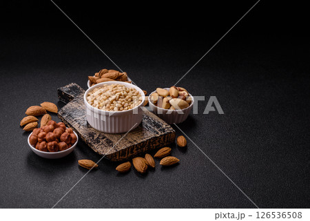 Peeled pine nuts in a bowl on a dark concrete background 126536508