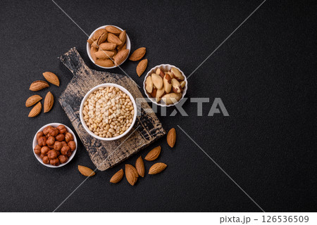 Peeled pine nuts in a bowl on a dark concrete background Peeled pine nuts in a bowl on a dark concrete background 126536509