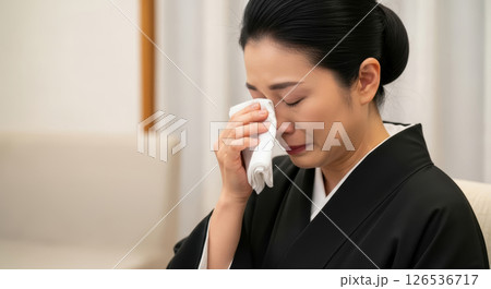 涙を拭う礼服の女性のクローズアップ（AI生成画像） 126536717