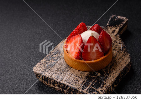 Round sweet tart with strawberry pieces and cream 126537050