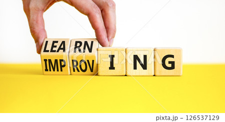 Improving or learning symbol. Businessman turns wooden cubes and changes the word Improving to Learning . Beautiful white background. Educational business improving or learning concept. Copy space. 126537129