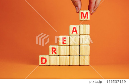 Dream symbol. Concept word Dream on beautiful wooden blocks. Beautiful orange table orange background. Businessman hand. Business lifestyle dream concept. Copy space. Dream symbol. Concept word Dream on beautiful wooden blocks. Beautiful orange table orange background. Businessman hand. Business lifestyle dream concept. Copy space. 126537139