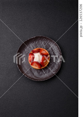 Round sweet tart with strawberry pieces and cream 126537206