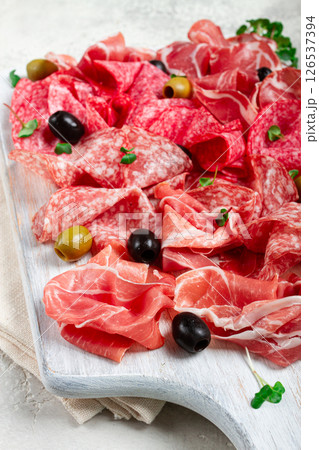 Assorted, meat appetizer, prosciutto, salami and ham, with olives , on a wooden white board, light background, breakfast, top view, close-up, no people 126537394