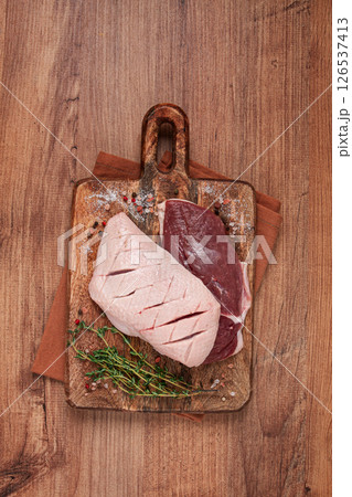 Fresh raw duck breasts, on a wooden chopping board, with herbs and spices, no people 126537413