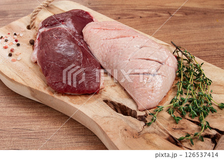 Fresh raw duck breasts, on a wooden chopping board, with herbs and spices, no people 126537414