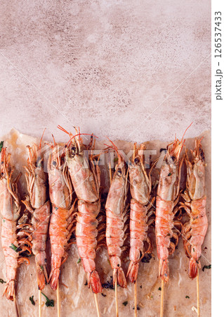 shrimps on skewers, Grilled, spread on a marble surface, garnished, with lemon slices, and fresh herbs, view from above, 126537433