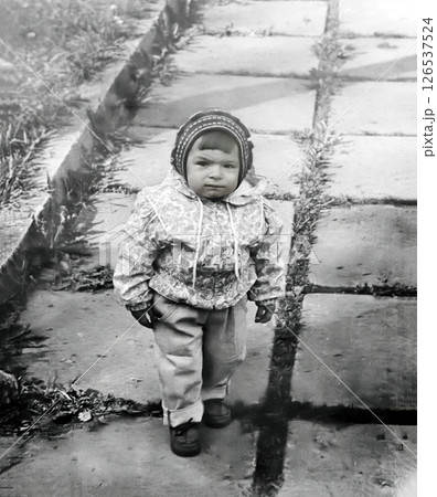 Vintage portrait of a little serious girl walking along a path in the park in spring. Retro photo 1995. Vintage portrait of a little serious girl walking along a path in the park in spring. Retro photo 1995. 126537524