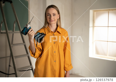 Woman holding cordless drill doing home renovation work 126537978