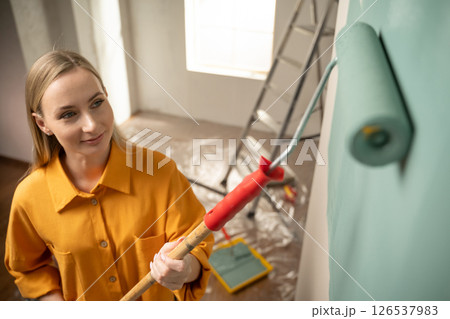 Woman painting wall with roller in new apartment renovation project 126537983