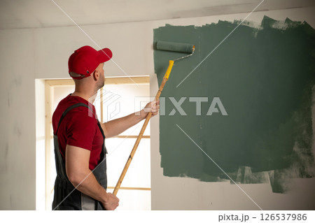 Painter painting wall with paint roller in new house 126537986