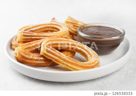 Traditional spanish dessert churros, fried dough pastry and chocolate sause on white background 126538333