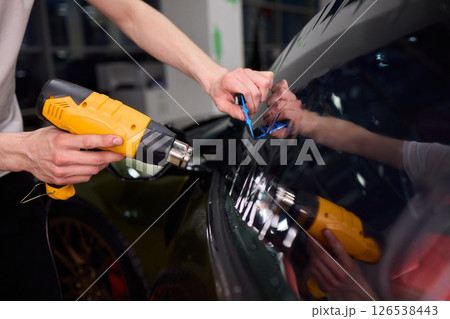 The Professional Windshield Tinting Process Conducted in a Modern Auto Showroom Environment The Professional Windshield Tinting Process Conducted in a Modern Auto Showroom Environment 126538443