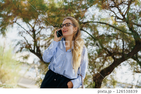 A young woman is engaged in a cheerful phone conversation while enjoying the great outdoors A young woman is engaged in a cheerful phone conversation while enjoying the great outdoors 126538839