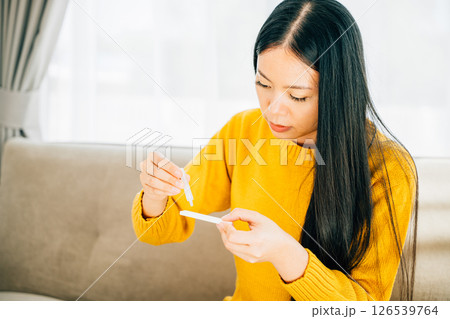 Illustrating COVID-19 self-test, Woman at home uses a rapid antigen test kit inserting a swab into her nose. Depicting virus prevention and pandemic protection measures. Illustrating COVID-19 self-test, Woman at home uses a rapid antigen test kit inserting a swab into her nose. Depicting virus prevention and pandemic protection measures. 126539764