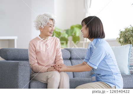 笑顔で話をするシニア女性と介護スタッフ 笑顔で話をするシニア女性と介護スタッフ 126540422