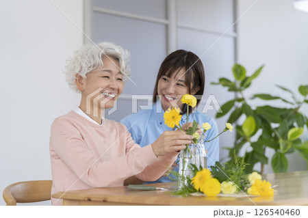 フラワーアレンジメントを楽しむシニア女性と介護スタッフ 126540460