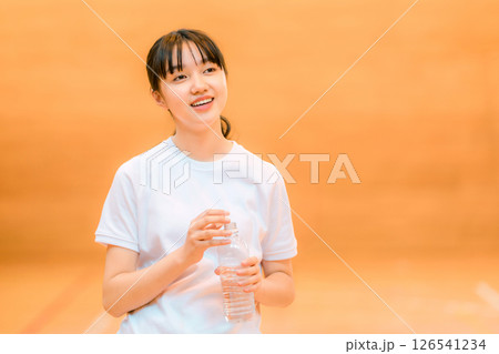 体育館でペットボトルの水で水分補給するジャージ姿の小学生,中学生,高校生の女の子 体育館でペットボトルの水で水分補給するジャージ姿の小学生,中学生,高校生の女の子 126541234
