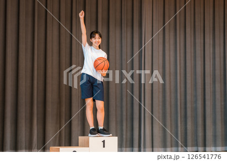 体育館のステージで表彰台に乗る体操着姿の小学生,中学生,高校生の女の子 126541776