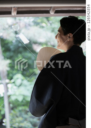 軒下の風鈴を眺める男性 お中元などの夏の涼感があるイメージ 軒下の風鈴を眺める男性 お中元などの夏の涼感があるイメージ 126542854