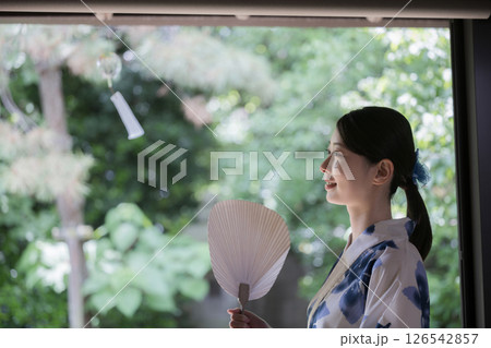 軒下の風鈴を眺める女性 お中元などの夏の涼感があるイメージ 軒下の風鈴を眺める女性 お中元などの夏の涼感があるイメージ 126542857