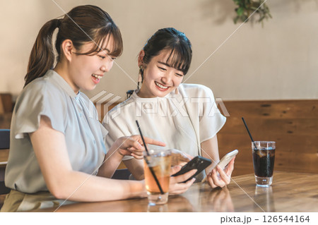 カフェや喫茶店でスマホを見ながら話す若いアジア人女性 126544164