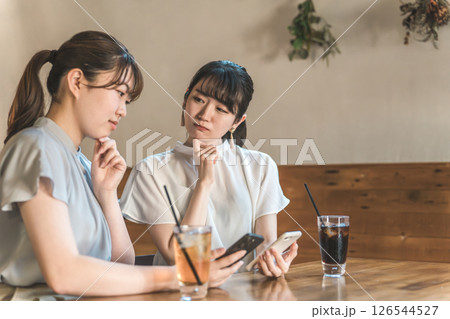 ランチを食べに来たカフェや飲食店の口コミ・SNSをスマホで見るアジア人女性 126544527