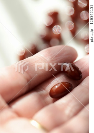 プラセンタサプリメントを2粒を乗せた50歳代女性の手 プラセンタサプリメントを2粒を乗せた50歳代女性の手 126545155