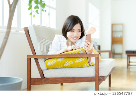 リビングでスマホを操作する若い女性 126547787