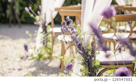 Aisle with wooden chairs and purple lavender floral decorations at an outdoor wedding ceremony in the garden 126547881