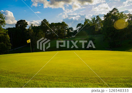 Beautiful golf course in a sunny day. Background evening golf course has sunlight shining down. Beautiful golf course in a sunny day. Background evening golf course has sunlight shining down. 126548333