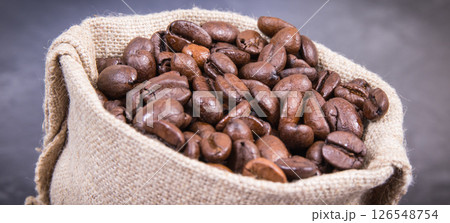 Heap of dark roasted coffee grains in jute bag 126548754