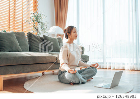 Happy young Asian woman practicing yoga and meditation at home sitting on floor 126548983