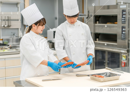 魚を調理するコックコート姿の男女スタッフ（調理師・専門学校・料理人・生鮮市場・食品加工） 126549363
