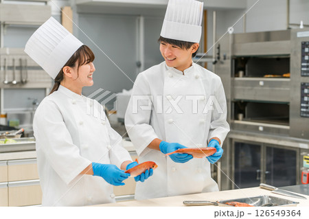 魚を調理するコックコート姿の男女スタッフ(調理師・専門学校・料理人・生鮮市場・食品加工) 魚を調理するコックコート姿の男女スタッフ(調理師・専門学校・料理人・生鮮市場・食品加工) 126549364