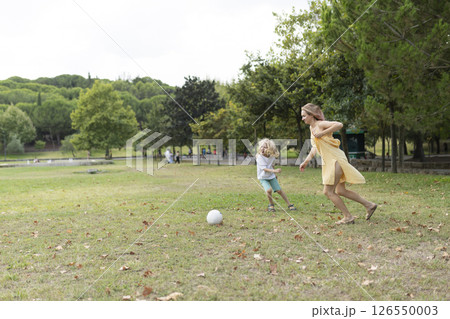 Mother and son running and playing soccer in a sunny park Mother and son running and playing soccer in a sunny park 126550003