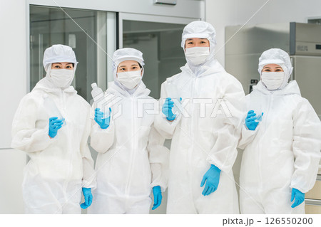 水工場,飲料メーカーで働くペットボトルの水を持つ防塵服姿の製造スタッフ 126550200