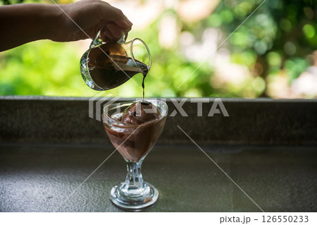 Affogato hot fudge poured chocolate ice cream in glass cup 126550233