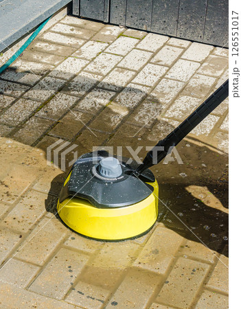 High-pressure cleaning tool is used on wet paving stones for thorough outdoor cleaning. High quality photo 126551017