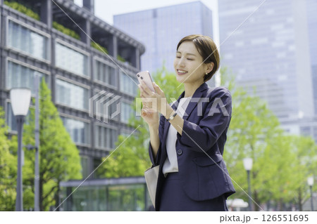 オフィス街でスマホで検索する若いビジネスウーマン 126551695