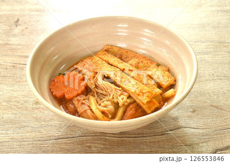 udon noodles topping slice fish tofu and needle mushroom with carot in kimchi soup on bowl 126553846