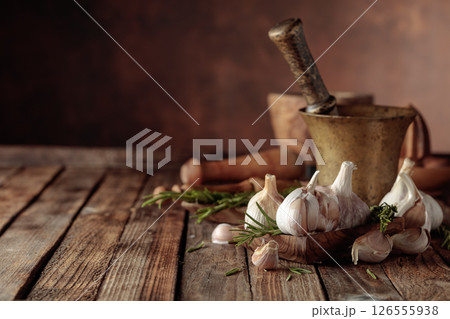 Fresh garlic bulbs with rosemary on a wooden table. Fresh garlic bulbs with rosemary on a wooden table. 126555938