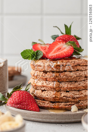 Oatmeal belgian waffles with strawberry, honey and almond petals stacked on a plate, white background 126556863