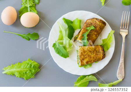 Appetizing omelette with greens and arugula on a white plate 126557352