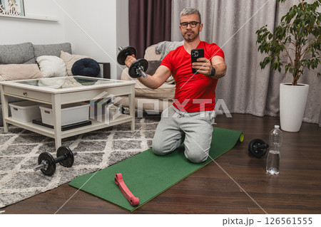 Man exercises indoors while using dumbbells in a home gym 126561555