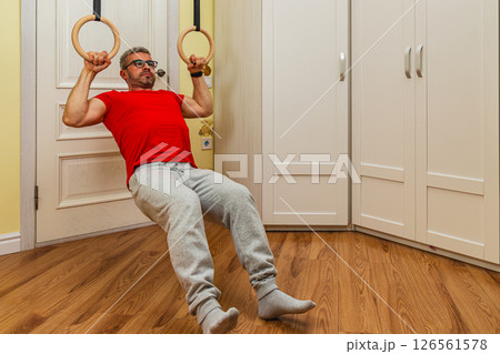 Man performs pull-ups on gymnastic rings indoors 126561578