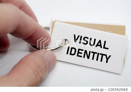 Visual identity concept presented on white notepad with hand holding it in clean workspace. Visual identity concept presented on white notepad with hand holding it in clean workspace. 126562668