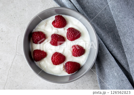 Natural fresh greek yogurt with red raspberry berries in dark plate and napkin for healthy breakfast.  126562823