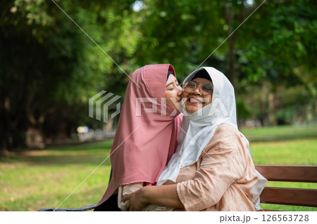 Muslim careful caregiver or nurse taking care of the patient in the hospital park. Happy Muslim mother in hijab hugging daughter. Concept of Savings and Senior Health Insurance, a Happy Family 126563728